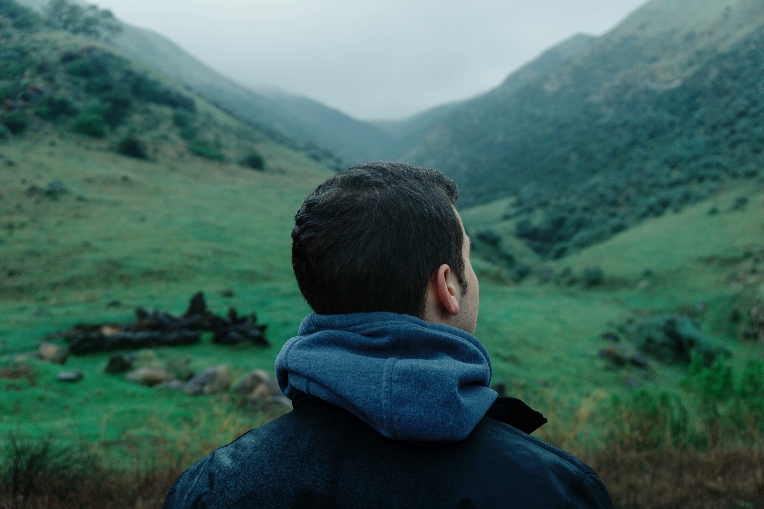 Photo of a male hiker standing between two hills, head turned toward the right