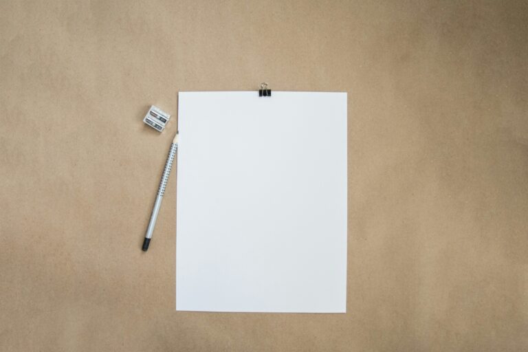 Photograph of a blank sheet of paper, pencil and pencil sharpener on a wood-colored desktop