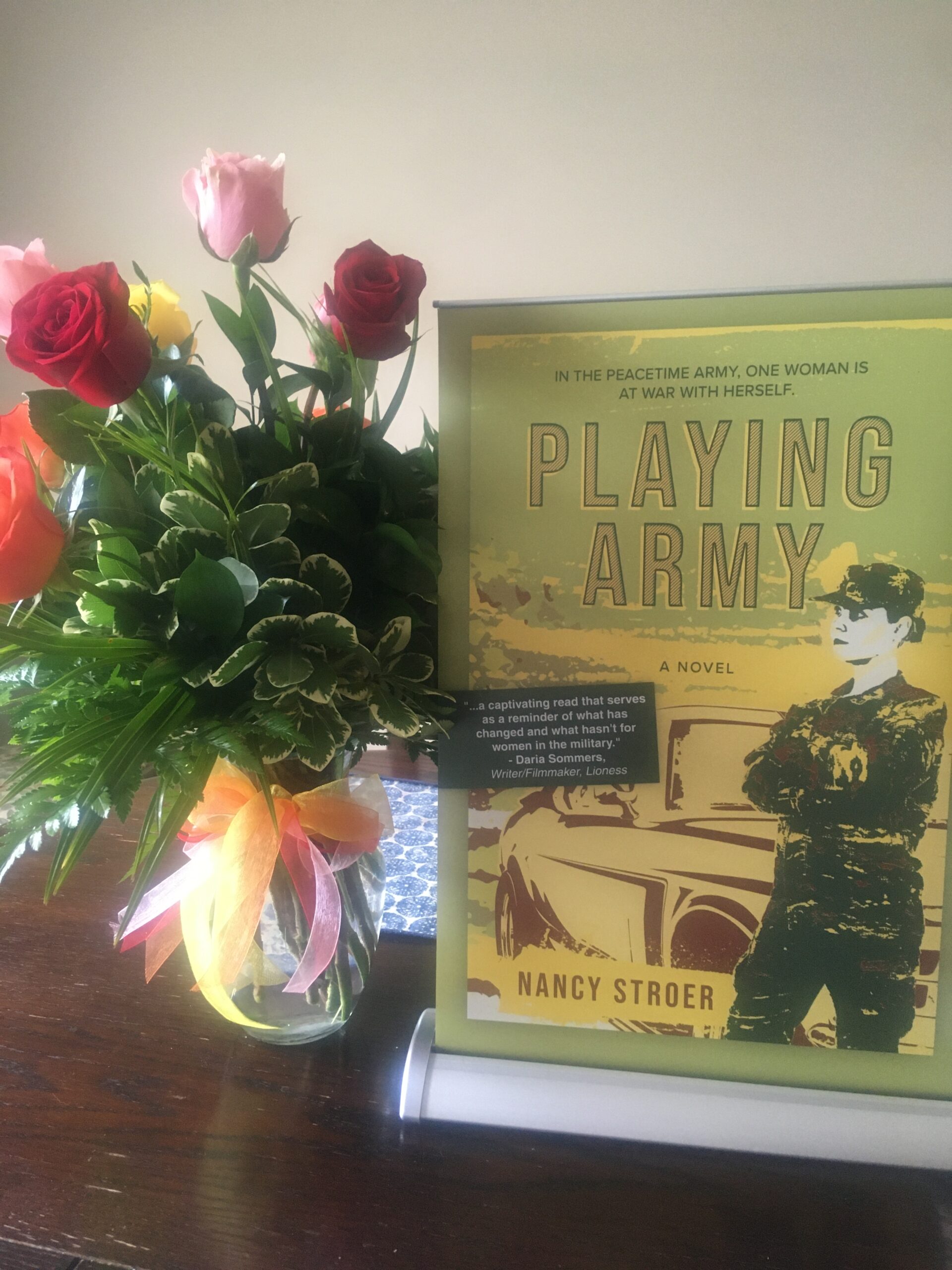 A beautiful bouquet of flowers in front of a table display showing the cover of Playing Army
