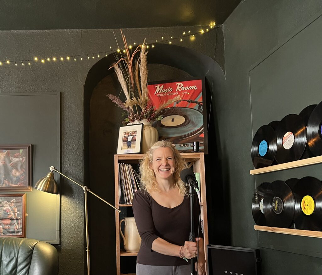 A photo of Leah upstairs at The Portly Pig (note pig artwork in the background, left), setting up the mic before a bunch of Ripon poets do their thing